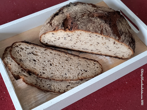 Anschnitt einen halben runden Laibes Dinkel-Buttermilchbrot mit 2 Scheiben davor
