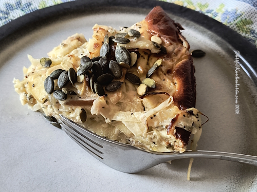 Apfel-Zwiebel-Quiche mit Mohn auf einem Teller mit Gabel angerichtet
