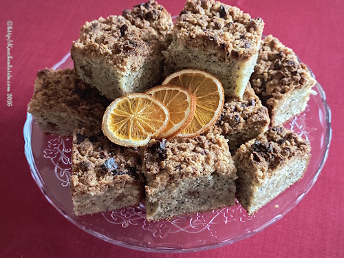 Orangen-Ricotta-Mohn-Kaffee-Kuchen verschiedene Stücke auf Glastortenplatte mit Fuß auf roter Tischdecke