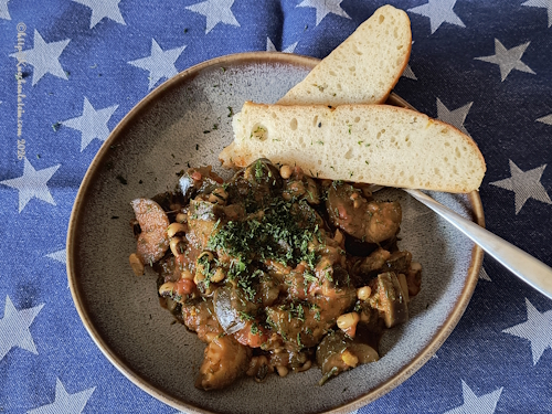 Augenbohnencurry mit Auberginen und Dill auf Teller mit Brot angerichtet