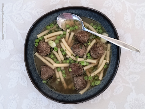 angerichteter Teller mit Fleischbällchen mit Pasta und Erbsen,