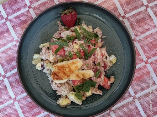 Teller mit Graupensalat mit Kichererbsen, Erdbeeren und Rhabarber Dressing, angerichtet mit Halloumi und Erdbeere