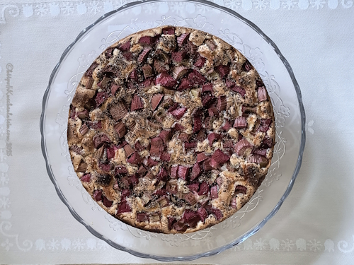 Ein ganzer Rhabarberkuchen mit Kardamom auf einer Glasplatte 